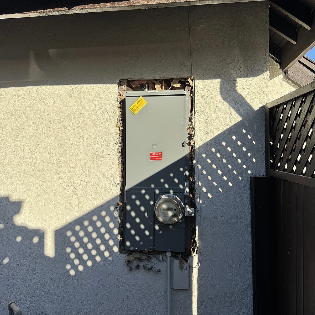 Exterior electrical service panel and utility meter installed on a stucco home