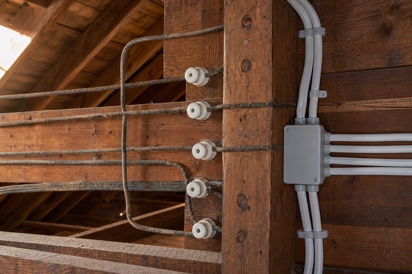 Historic knob-and-tube wiring in attic framing beside modern replacement wiring